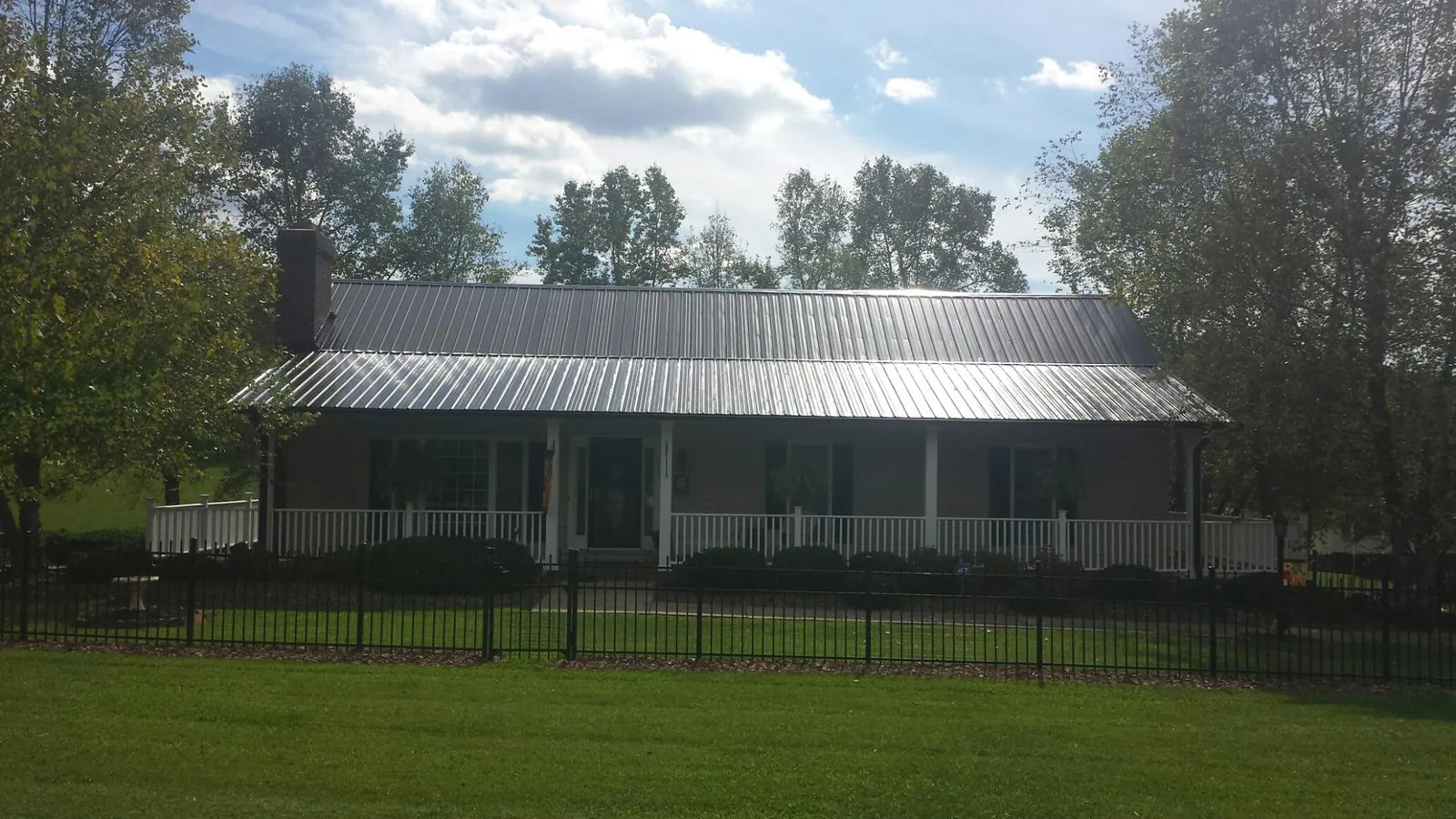 Gray metal roof on a brick ranch with a full width front porch — Gutter Guard Installation work by our crew in Harrison